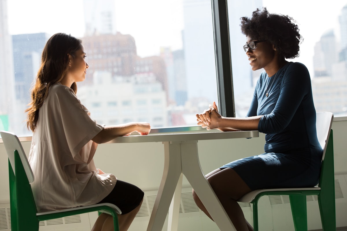 Duas pessoas conversam à mesa durante uma reunião.